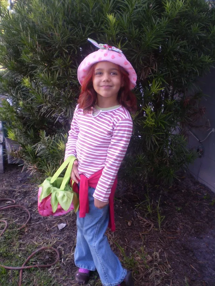 Young girl dressed in a playful Halloween costume holding a colorful bag with children's Halloween costume ideas theme.