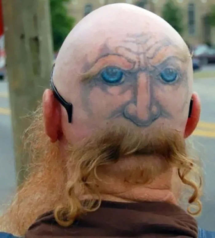 Bald head with a tattooed face and curly hair on the neck, showcasing one of the craziest haircuts ever.