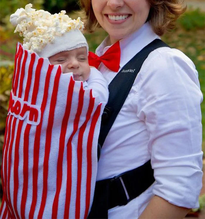 Baby dressed as a popcorn bag in a creative children's Halloween costume idea carried by a smiling adult.