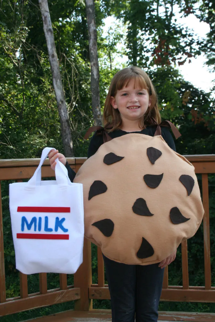 Young girl wearing a cookie costume and holding a milk bag, creative children's Halloween costume ideas outdoors.