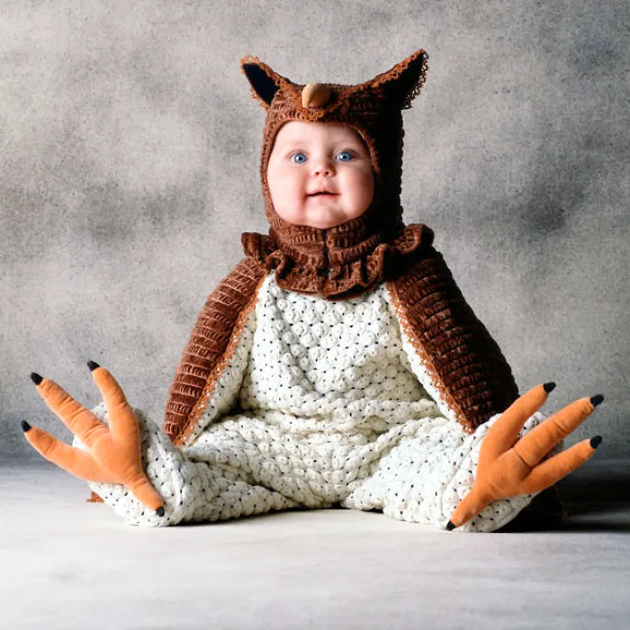 Baby dressed in a detailed bird costume sitting against a plain background, showcasing creative children's Halloween costume ideas.