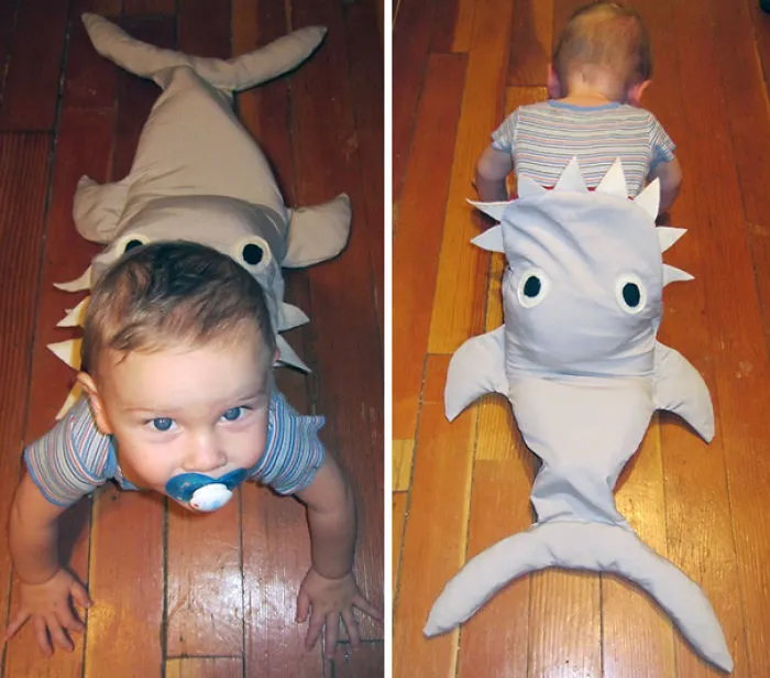 Toddler wearing a shark costume crawling on hardwood floor showing creative children's Halloween costume ideas.