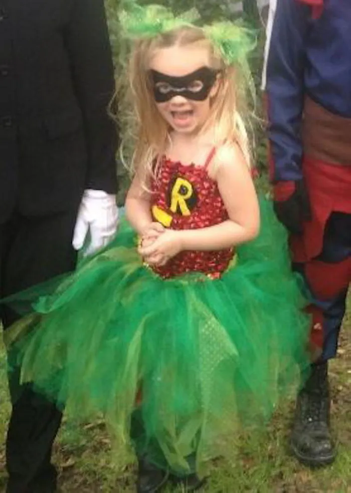 Young girl in a vibrant superhero costume with green tutu and black mask, showcasing creative children's Halloween costume ideas.