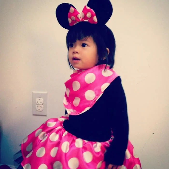 Young child dressed in a pink polka dot costume with mouse ears for children's Halloween costume ideas.