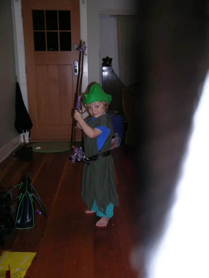 Child dressed in a fantasy costume holding a staff indoors, perfect example for children's Halloween costume ideas.