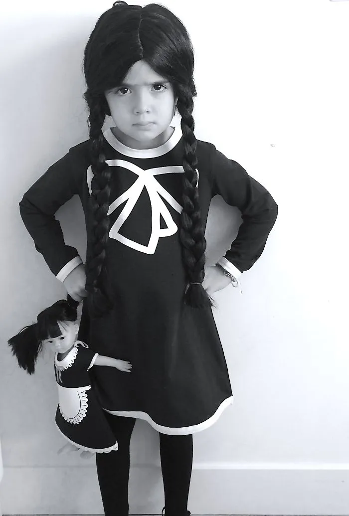 Child in Halloween costume standing with matching doll, showcasing creative children's Halloween costume ideas.