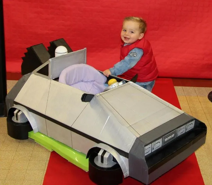 Toddler smiling with a creative car costume, a fun idea for children's Halloween costume ideas.