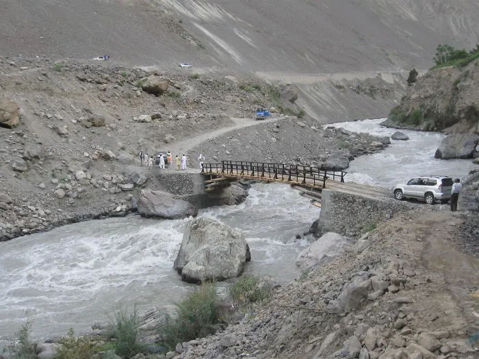 Rustic wooden bridge over a flowing river in a mountainous landscape, showcasing mystical bridges in remote natural settings.