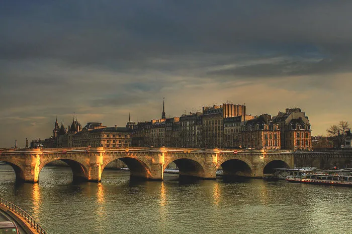 Stone bridge over calm river at sunset with historic buildings in the background, showcasing mystical bridges and serene atmosphere.