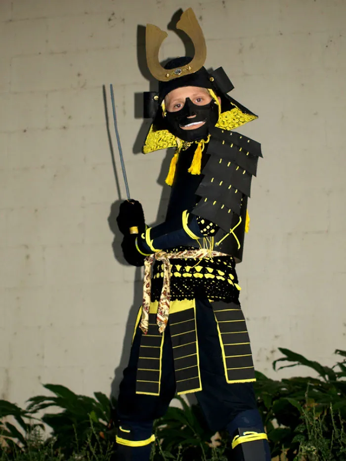Child dressed in an elaborate samurai Halloween costume, posing with swords for children's Halloween costume ideas.