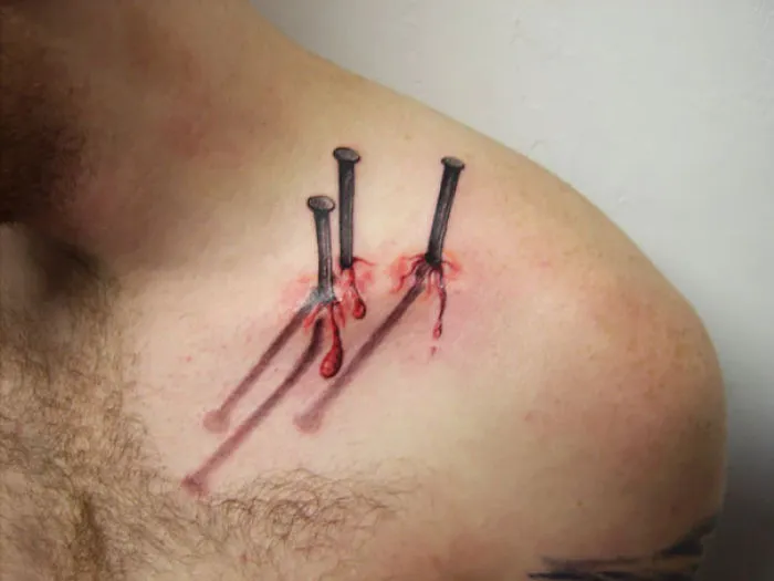 3D tattoo of realistic nails with shadows and blood effect on a person's shoulder.