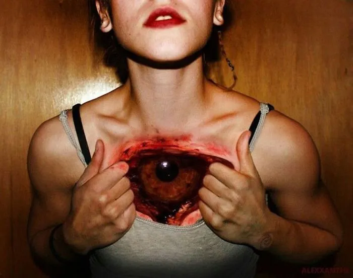 Person with a realistic 3D tattoo of an eye on their chest, creating a surreal and mind-bending effect.