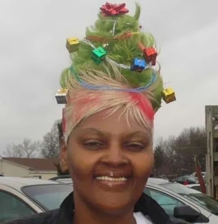 Person with a crazy haircut styled like a Christmas tree, decorated with ornaments and colorful highlights.