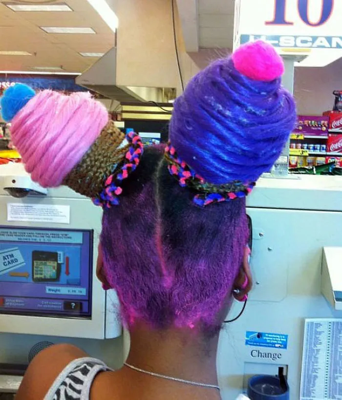 A person with a crazy hairstyle resembling two colorful ice cream cones, featuring pink and purple tones.