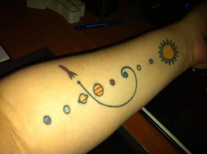 Colorful cosmic tattoo on arm featuring planets and sun, perfect for astronomy lovers.