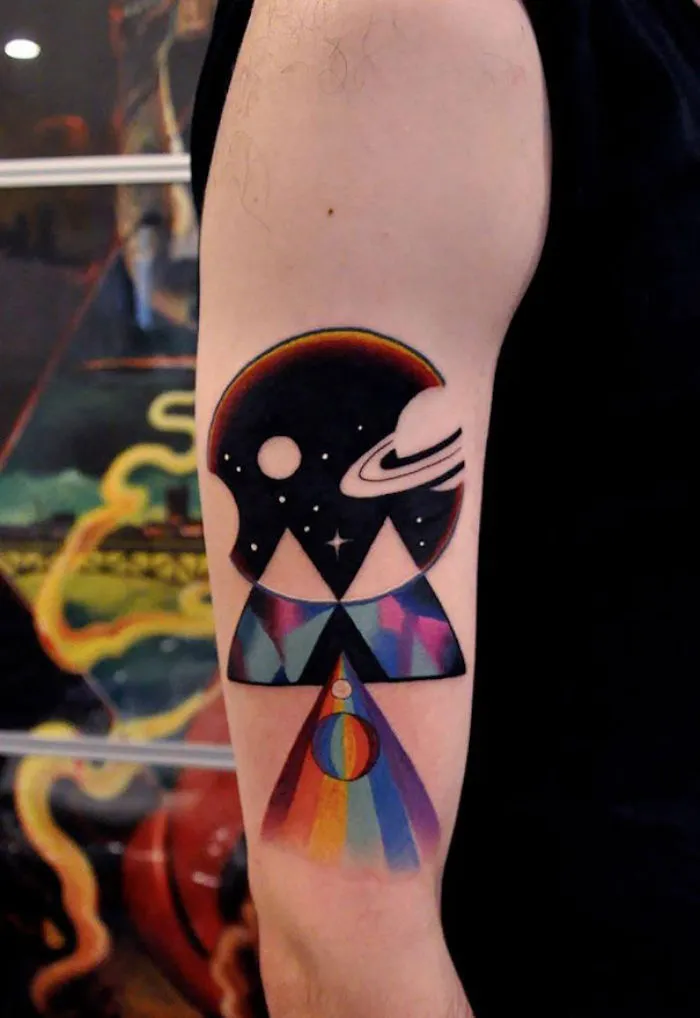 Colorful cosmic tattoo on arm featuring geometric shapes and space elements. Ideal for astronomy enthusiasts.