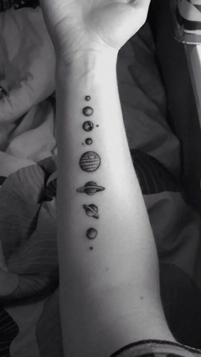Arm tattoo with small planets, ideal for astronomy lovers.