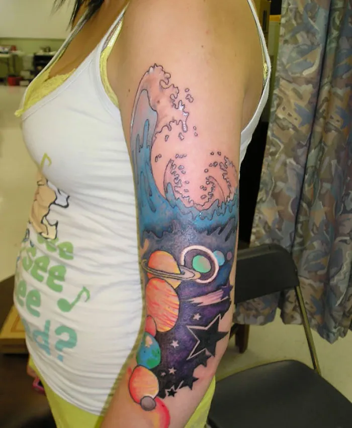 Colorful cosmic tattoo with planets and waves on an arm, perfect for astronomy lovers.