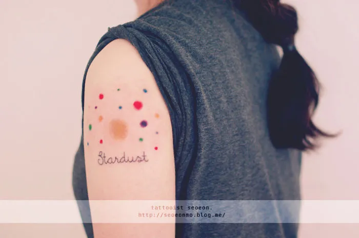 Colorful stardust arm tattoo featuring cosmic elements for astronomy lovers.
