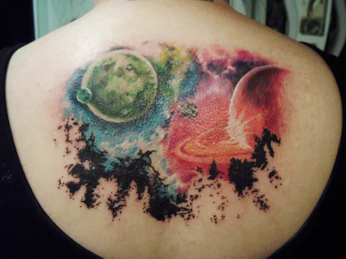 Colorful cosmic tattoo on back featuring planets and space scene, perfect for astronomy enthusiasts.