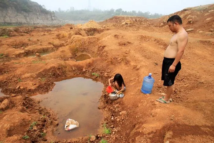 Girl And Her Father Collect Water From Puddle At Dried-up Reservoir, Baofeng County
