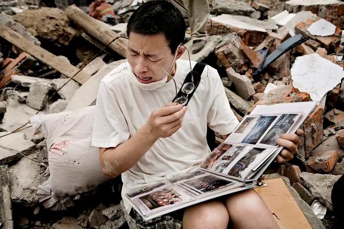 A Man Cries While Flipping Through A Family Album He Found In The Rubble Of His Old House