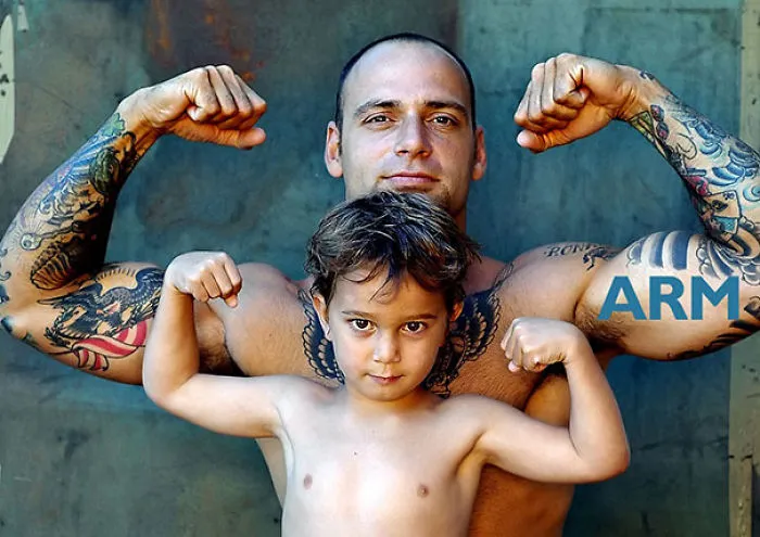 Tattooed parent and child posing together, flexing their arms with tattoos visible.