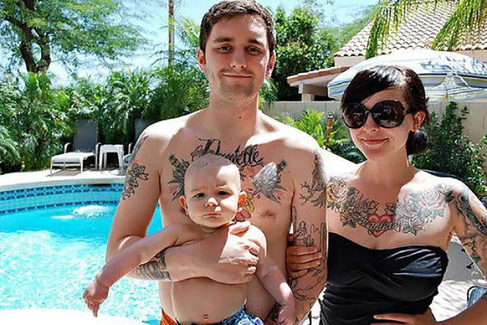 Tattooed parents with baby by the pool, showcasing beautiful family tattoos together.