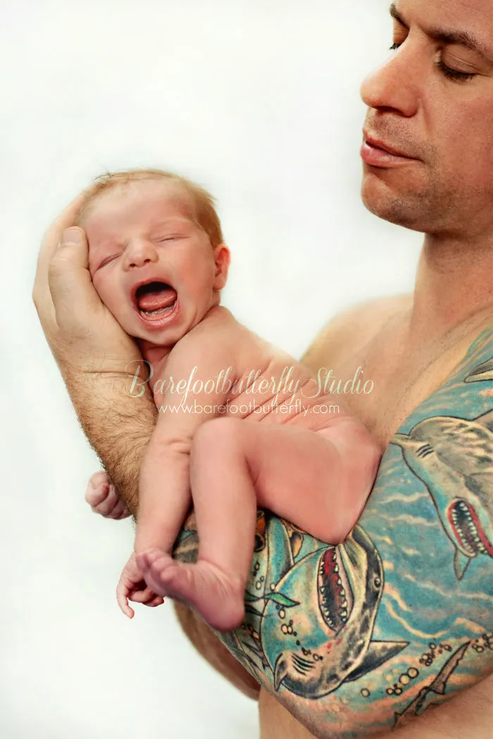 Tattooed parent gently cradling a newborn.