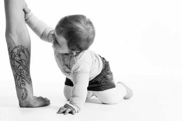 A baby touching a tattooed parent's leg, highlighting the beautiful bond between tattooed parents and their children.