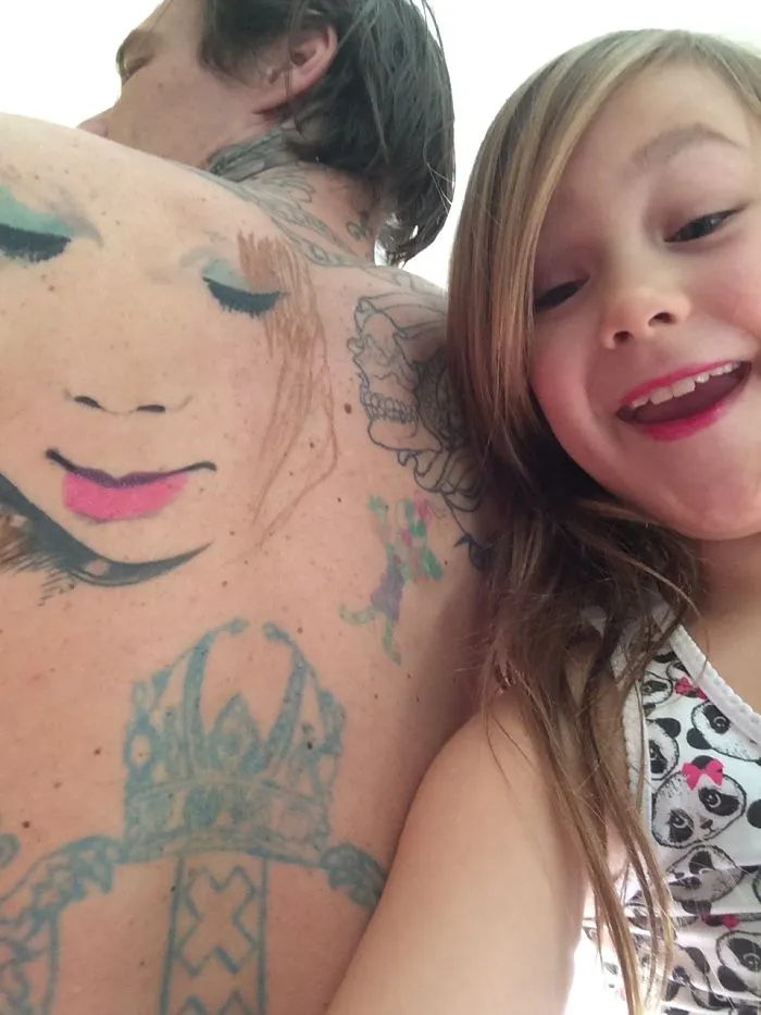Child with tattooed parent, showcasing body art and a joyful expression together.