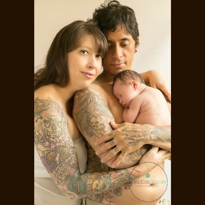 Tattooed parents lovingly holding their baby, showcasing beautiful body art in a tender family moment.