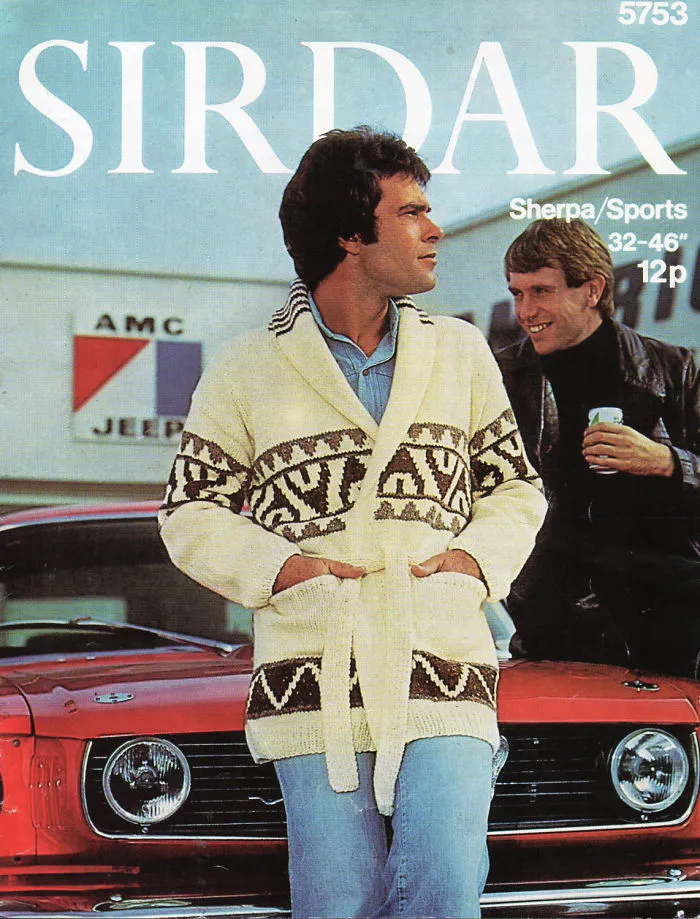Man wearing patterned cardigan in front of vintage car, showcasing 1970s men's fashion.
