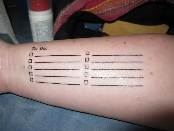 Forearm tattoo of a to-do list with checkboxes, inspired by Picasso's artistic style.