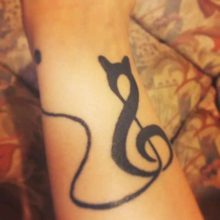 Simple cat tattoo line art design on arm.