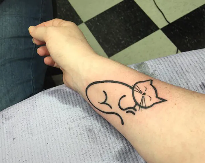 Simple line art cat tattoo on forearm for cat lovers.