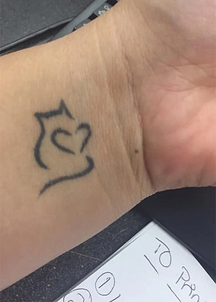 Simple line art cat tattoo on a wrist, showing minimalist design for cat lovers.