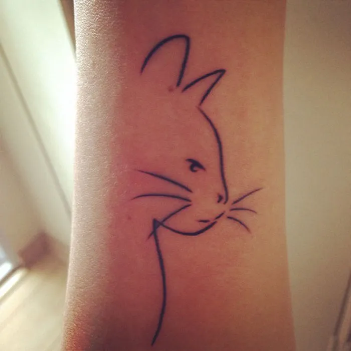 Simple cat tattoo design in line art style on arm, ideal for cat lovers.