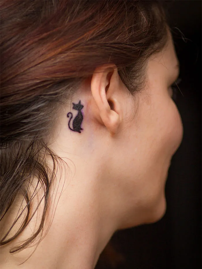 Line art cat tattoo behind ear, showcasing simple design for cat lovers.