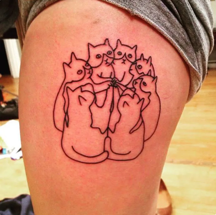 Line art tattoo of multiple cats on a person's thigh, showcasing simple cat design for cat lovers.