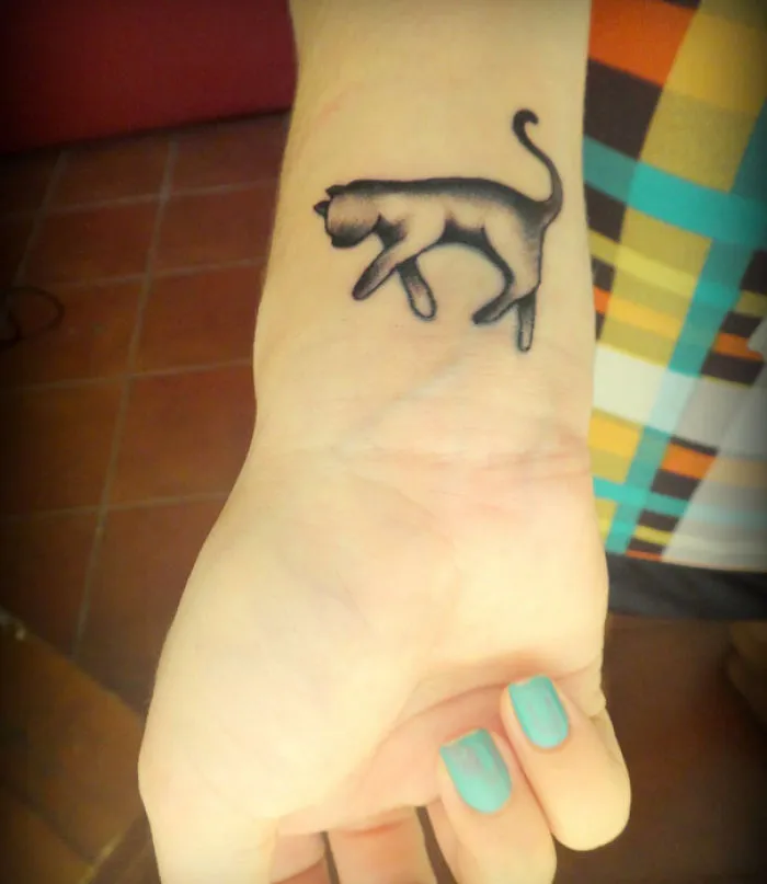 Minimalist line art cat tattoo on wrist, perfect for cat lovers.