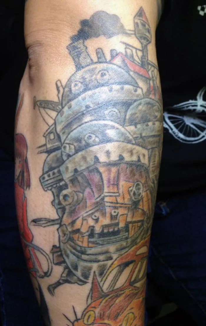 Studio Ghibli tattoo featuring Miyazaki film characters in vibrant colors on an arm.
