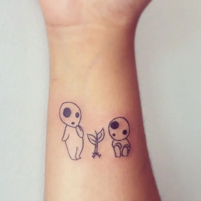 Studio Ghibli tattoo with two Kodama spirits and a young plant on forearm.