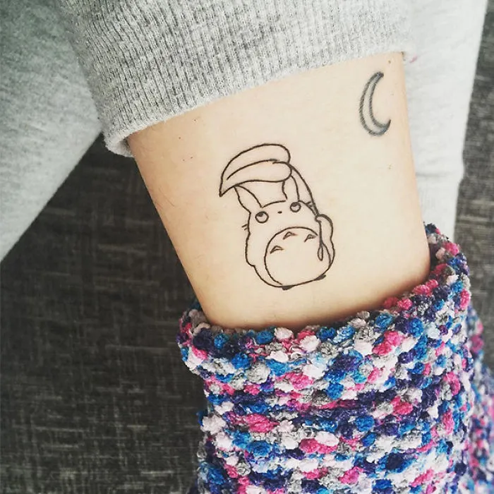 Studio Ghibli tattoo with Totoro design on an arm, inspired by Miyazaki films.