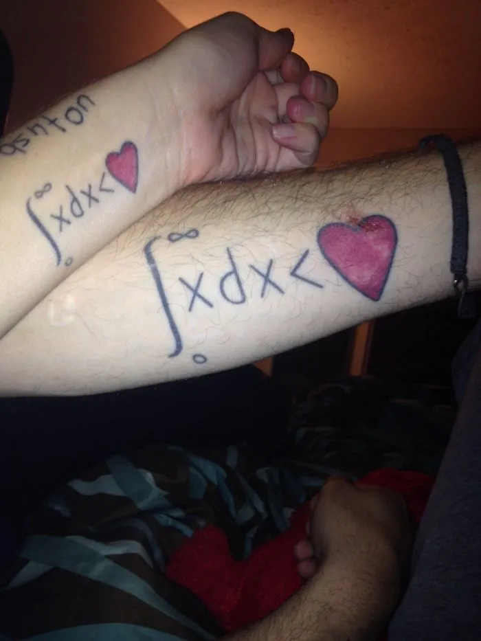 Matching tattoos with mathematical equations and hearts on a couple's wrists, symbolizing brave commitment.