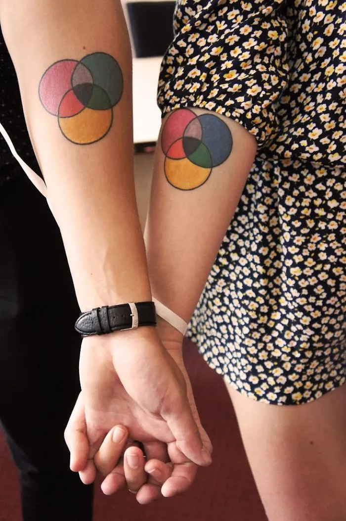 Matching wedding tattoos of colorful overlapping circles on a couple's arms.