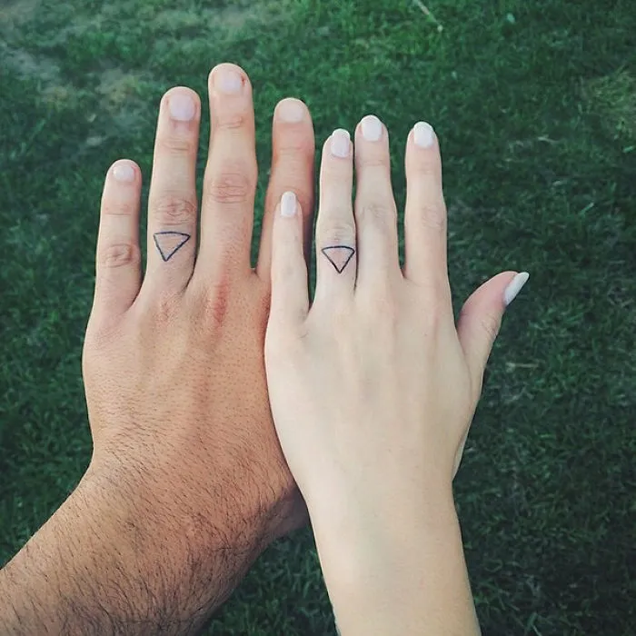 Matching wedding tattoos with triangle designs on a couple's ring fingers.
