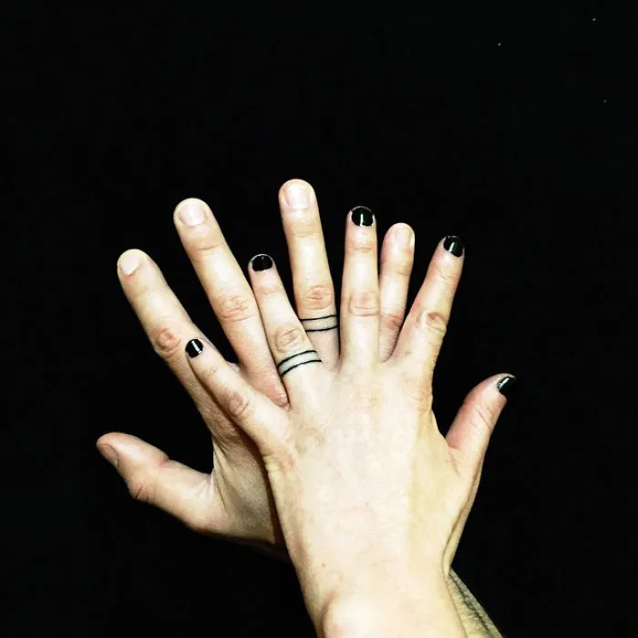 Matching wedding tattoos on a couple's ring fingers, replacing traditional rings.