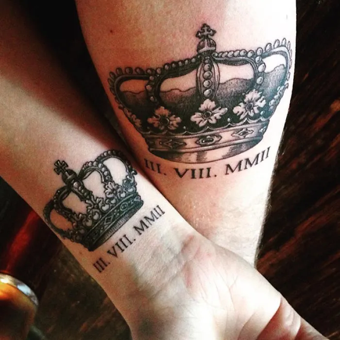 Matching couple wedding tattoos featuring crown designs with Roman numeral dates.