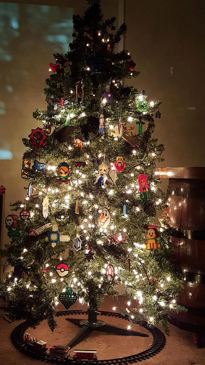 Cat perched in a decorated Christmas tree, surrounded by lights and ornaments.